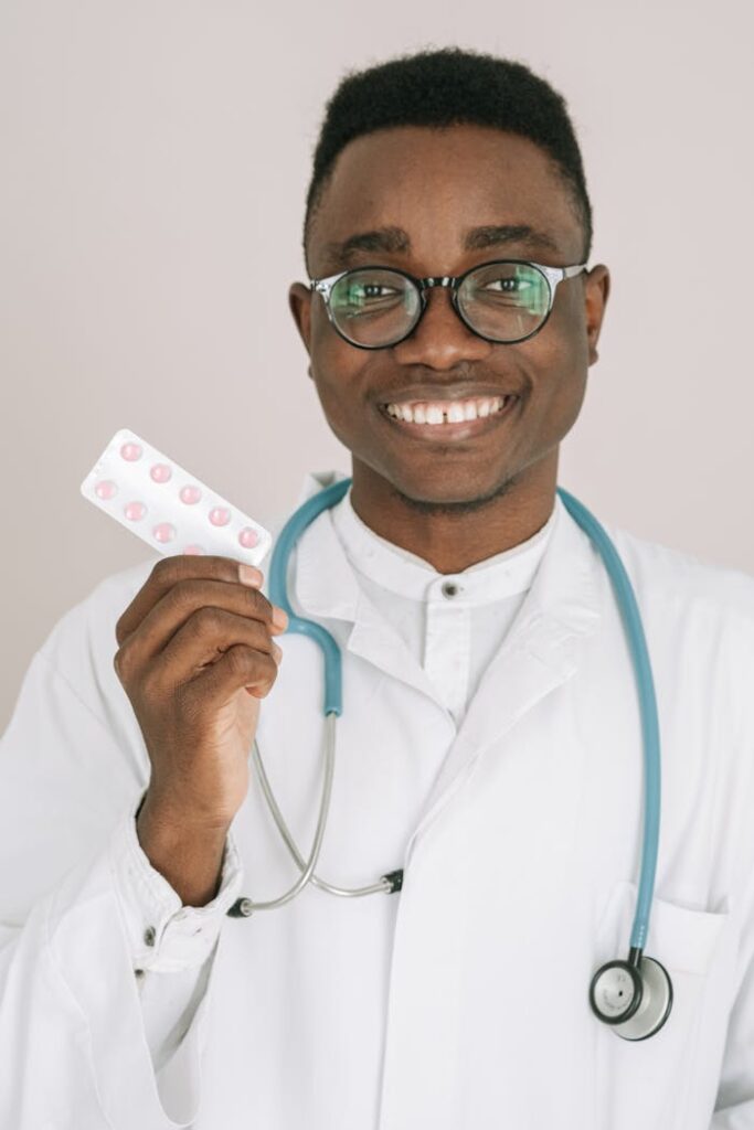 pexels photo 4989190 Portrait of a cheerful doctor in a white coat holding a blister pack of pills.