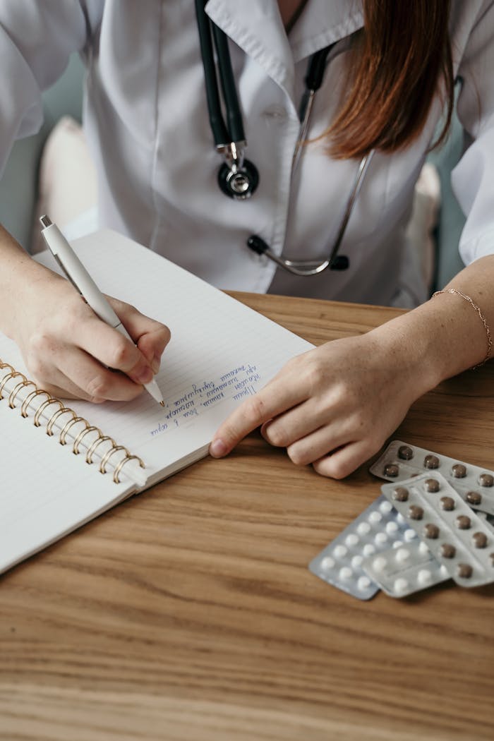 services-04 Close-up of a doctor writing a prescription with medicine on a wooden desk.