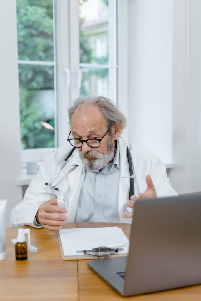 pexels photo 8376266 Elderly doctor explaining medication during an online consultation in a well-lit office setting.